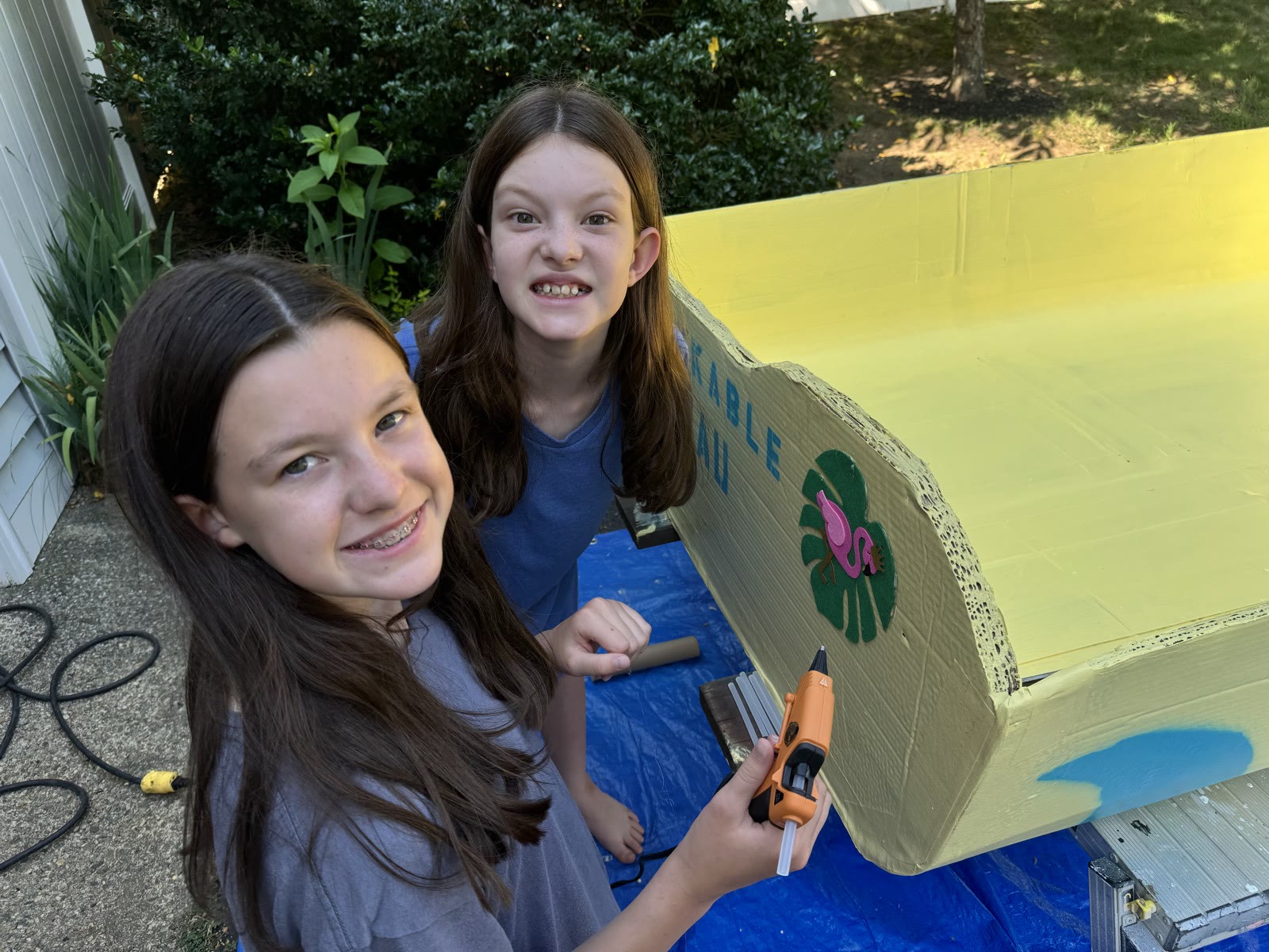 Two young builders decorating the corrugated hull of The BumbleMcBees